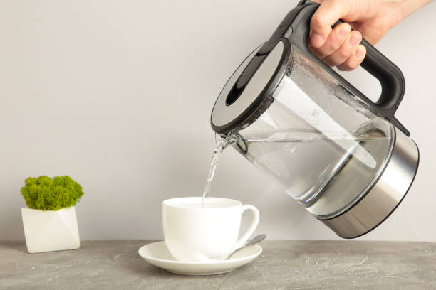 istock Kettle pouring boiling water into a cup on grey background. 1326558078
