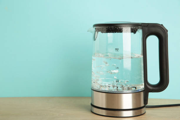istock Glass electric kettle with boiling water on blue background. 1326558721