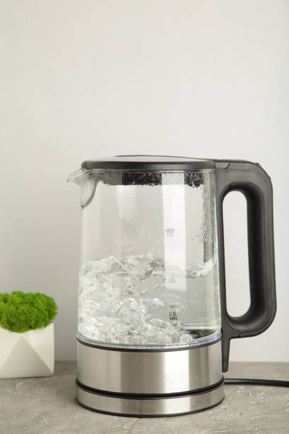 istock Glass electric kettle with boiling water on grey background. 1326558727