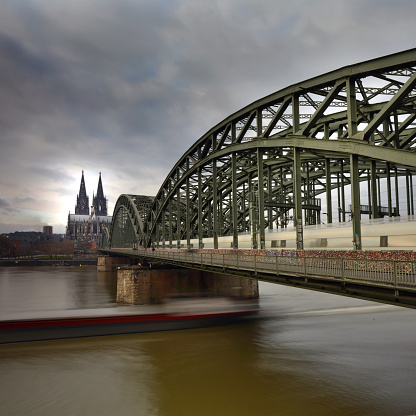 Longexposure shot of the Cologne Cathedral with the Hohenzollern Bridge and river Rhine in the foreground on a cloudy day in Cologne, Germany