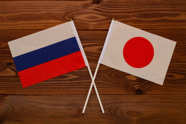 bandeira da rússia e bandeira do japão cruzou entre si. a imagem ilustra a relação entre os países. fotografia para notícias em vídeo na tv e artigos na internet e mídia. - president of russia - fotografias e filmes do acervo