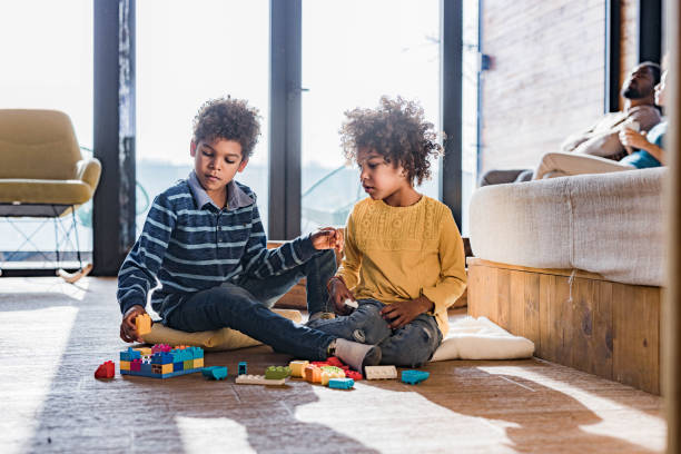 istock African American siblings playing with toy blocks at home. 1326563794