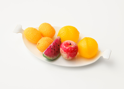 Overhead shot of old miniature toy fruits with white plate on white background