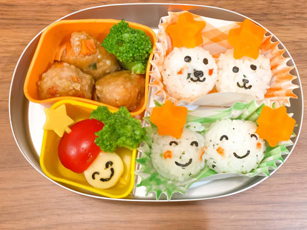 Cute home-packed meal for kids in the stainless steel lunch box with wooden table background