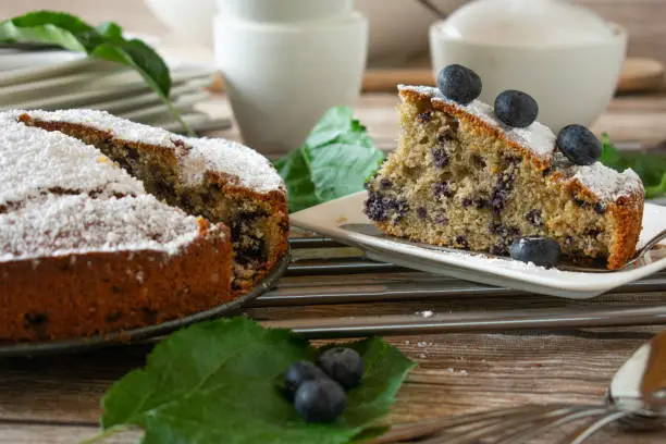 fresh and homemade baked gluten free and clean eating cake with blueberries made with almond flour and served on a rustic table background. Front view