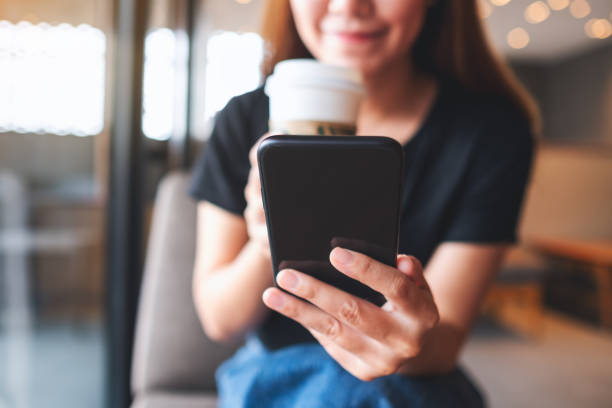 istock a beautiful young asian woman holding and using mobile phone while drinking coffee in cafe 1326567091