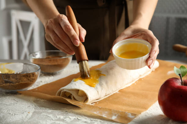 istock Woman making delicious apple strudel at table, closeup 1326569630