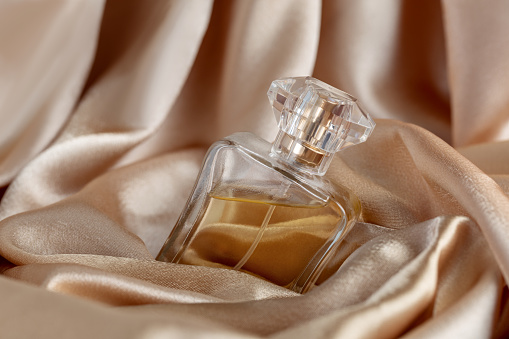 botella de vidrio de perfume sobre fondo de seda dorada photo