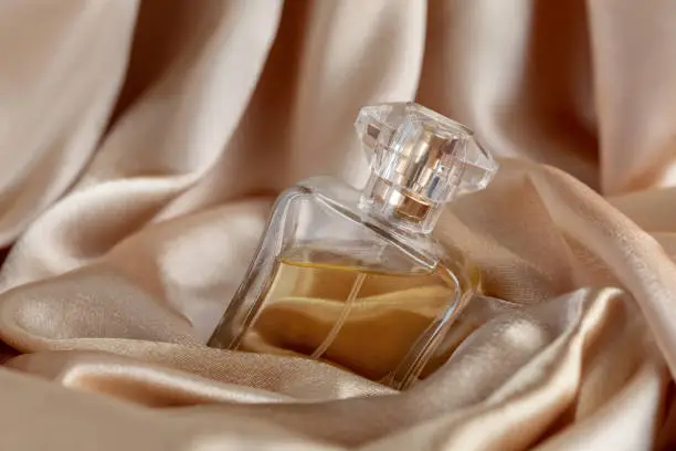 Photo of glass bottle of perfume on golden silk background