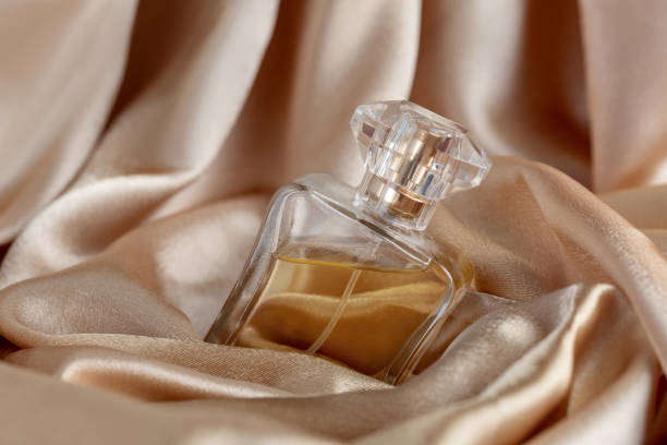 szklana butelka perfum na złotym jedwabnym tle - perfumy zdjęcia i obrazy z banku zdjęć