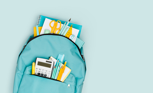 Close-up of school backpack with colorful stationery and text space