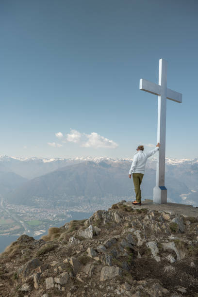 He carries a backpack, mountain range on background.\nTicino Canton, Switzerland