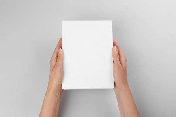 Woman holding book with blank cover on light grey background, closeup. Space for design Woman holding book with blank cover on light grey background, closeup. Space for design handbook photos stock pictures, royalty-free photos & images