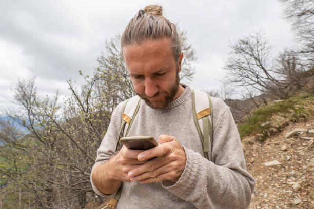 istock Man hiker uses phone on mountain trail 1326579288