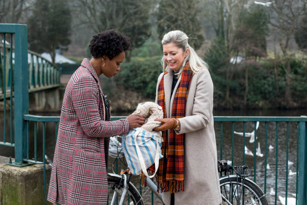 Sustainable Fashion Delivered To You Woman selling a handmade ethically sourced woollen cardigan. She is showing the garment to a woman who has met her in the park to purchase it. clothing swap photos stock pictures, royalty-free photos & images