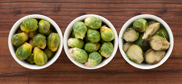 Top view of three bowls with brussels sprouts in different states (boiled, raw and grilled)
