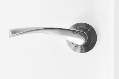 Metallic doorknob and keyhole on a white wooden door. Detail