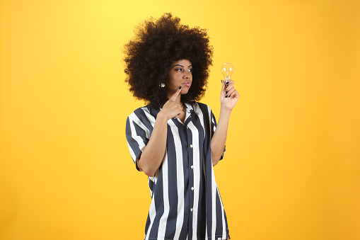 Mixed afro woman, with a light bulb, yellow background
