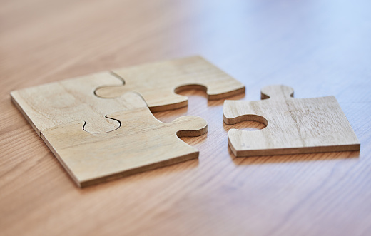 Shot of puzzle pieces lying on a desk in an empty office during the day