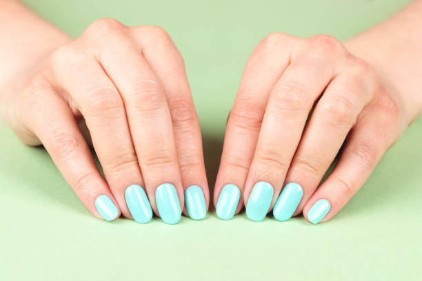 istock Hands with turquoise nails on green background 1326608530
