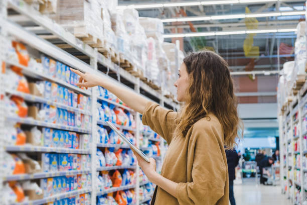 jovem empresária com um tablet seleciona produtos químicos domésticos em um supermercado - business pointing women index finger - fotografias e filmes do acervo