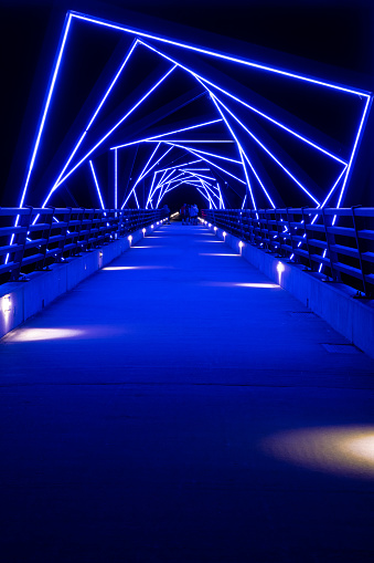 A bridge on a bike trail lit up in blue at night.