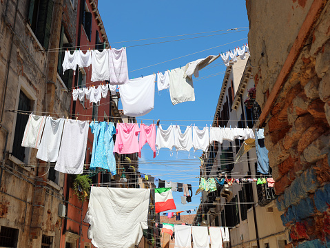 clothes hanging out drying in the sun in the narrow street of the typical Italian city