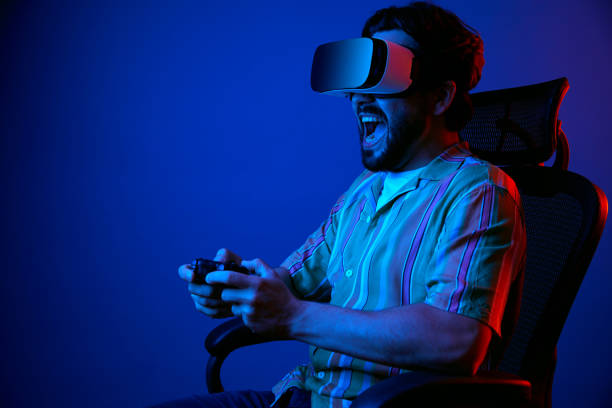istock Man shouting loudly while playing games in VR glasses, sitting on chair 1326613785