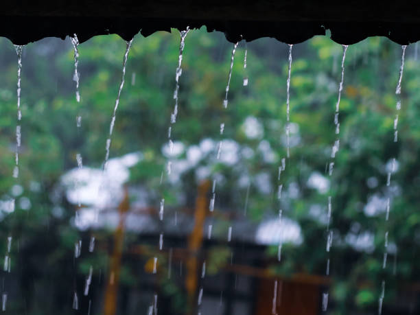 istock Raining outside with green background. Raining on a soil house rooftop. Raindrops with beautiful green background. 1326615120