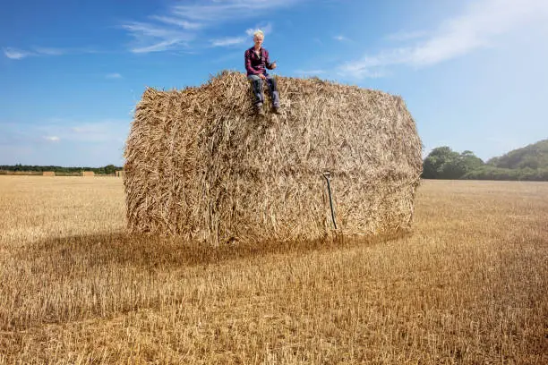 A man has done a great job. The man has collected a hay / straw for a huge straw bale