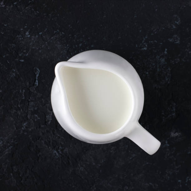 istock Whit milk jug with milk on a black background, top view. 1326616243