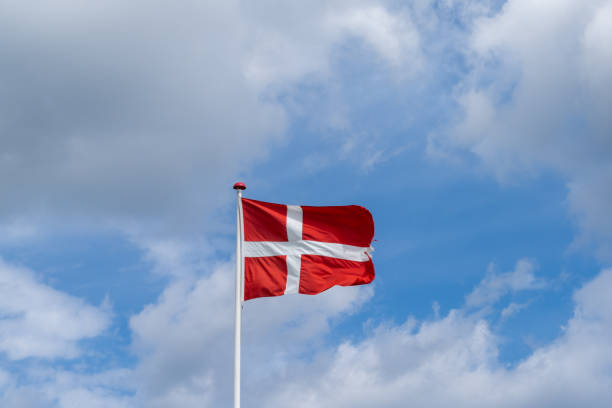 istock Danish flag flying in the wind under a blue sky with white cumuls clouds 1326616613