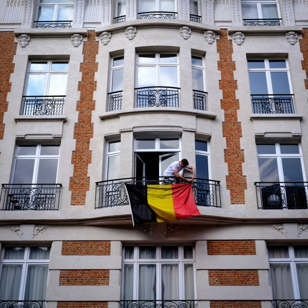 a man attaches a flag of belgium in a balcony in brussels, belgium on july 1st, 2021. - fifa torneio imagens e fotografias de stock
