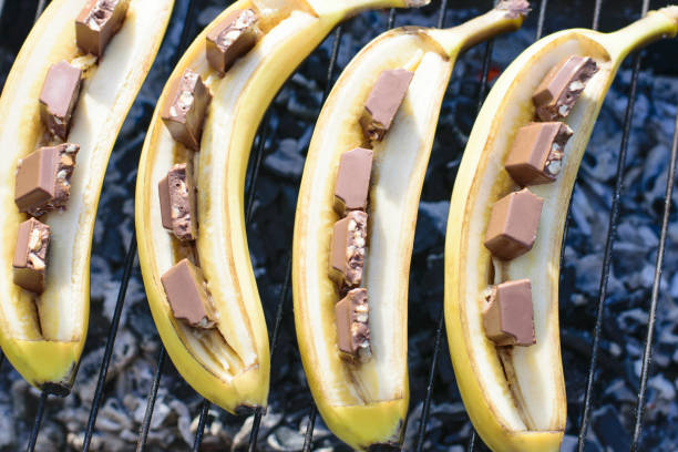 банан с шоколадом на гриле. сладкий десерт для пикника. - grilled bananas стоковые фото и изображения