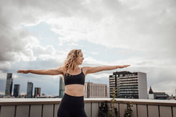 Women in yoga pose on a rooftop terrace stock photo