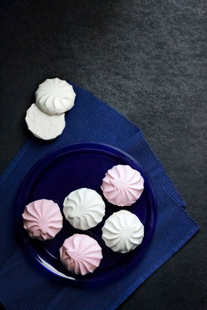 istock White and pink marshmallow on blue plate on black background 1326621119