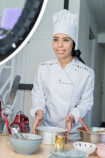 istock Female influencer chef speaks to her followers while doing a live show teaching how to prepare a cake using her light ring and her uniform 1326622473