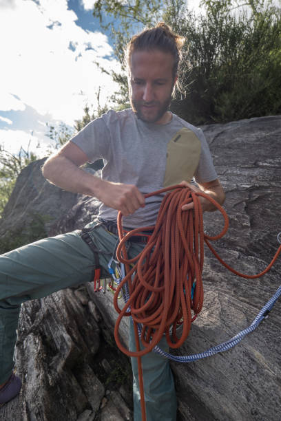 istock Man mountain climber prepares to rappel, sorts rope 1326622527