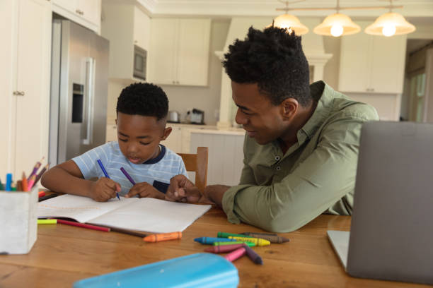 istock Happy african american father with son doing homework at home smiling 1326625697