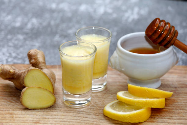 Ginger drink, juice or shot with healthy ingredients. Drink with ginger root, honey and lemon on wooden background. shot glass stock pictures, royalty-free photos & images