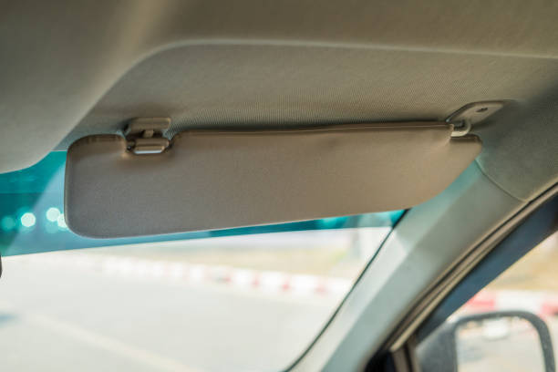 istock Car visor. Car interior. Grey open sun car visor with selective focus and car mirror on blurred background with automobile window 1326633916