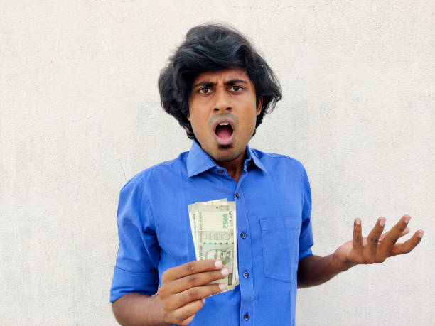 istock South Indian young man feeling extremely shocked and surprised holding two 500 rupees note. White background 1326634766