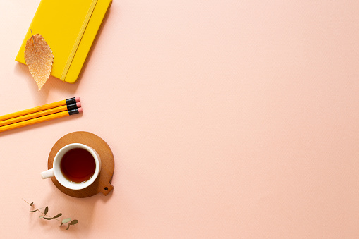 Notebook, cup of tea, pencil on pink background. flat lay, top view, copy space. Work and study place