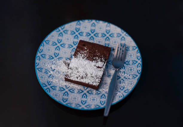 istock dark chocolate square shape brownie topping with icing sugar on black table 1326640765