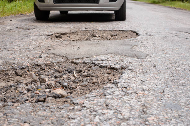 istock Car near many deep dangerous holes in asphalt surface 1326641791