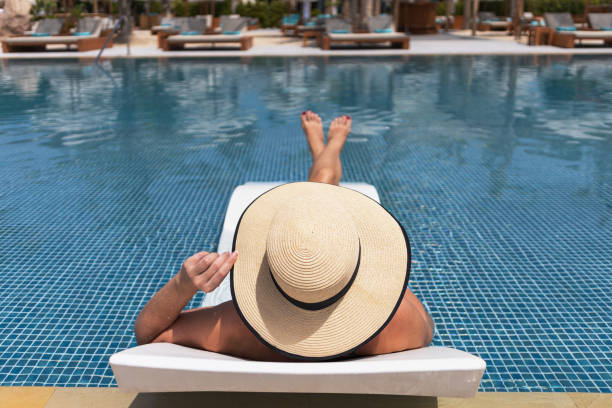 istock A woman in a hat relaxing at swimming pool 1326642979