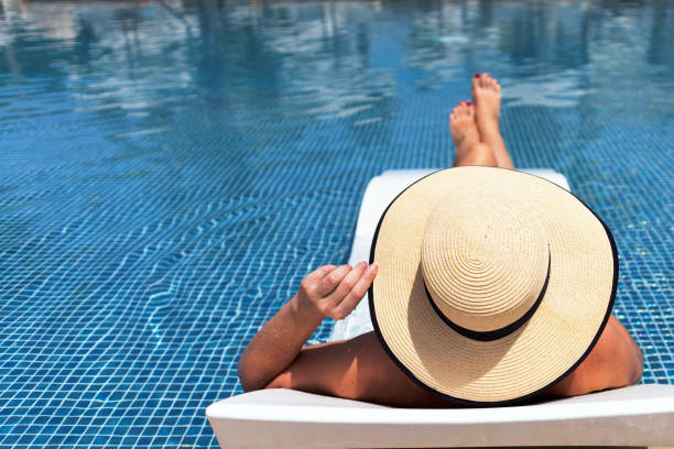 istock A woman in a hat relaxing at swimming pool 1326643193