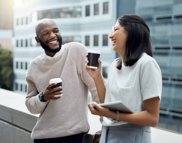 shot of two businesspeople drinking coffee together outside an office - colleague imagens e fotografias de stock