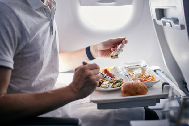 Airline meal served during flight Passenger eating airline meal. Menu in business class on medium haul flight. airplane food stock pictures, royalty-free photos & images