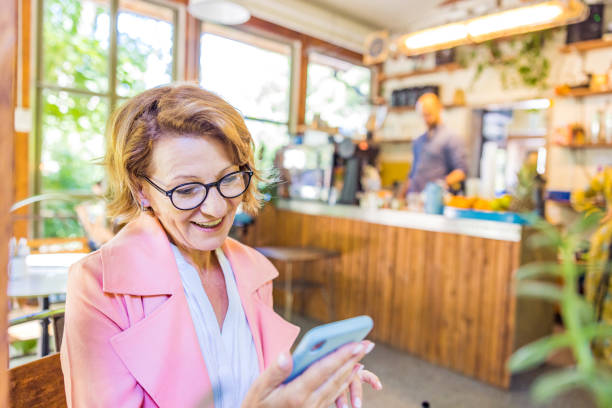 istock Senior woman attending a video call using smartphone at a cafe 1326645524